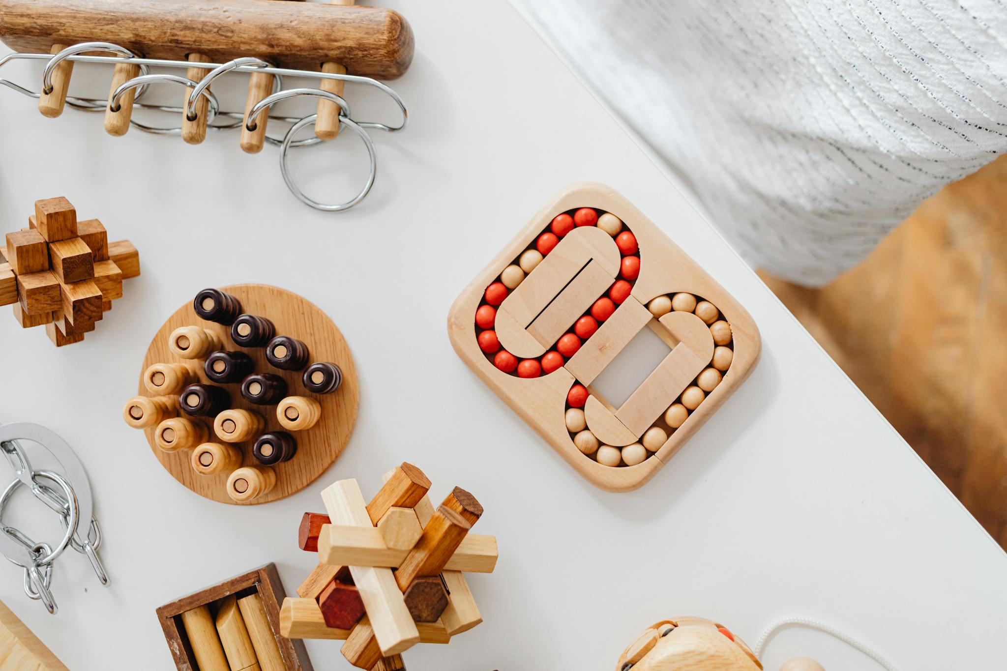 Overhead shot of various wooden puzzles and brain teasers on a white table.