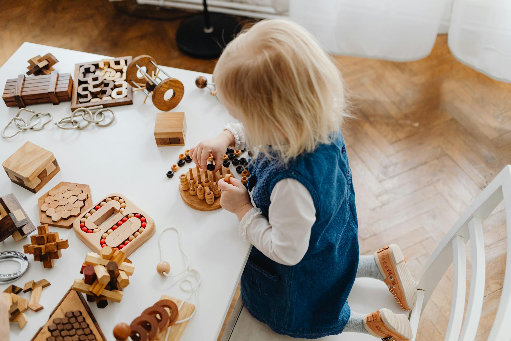 Young child playing with educational wooden toys on a table from a high angle view.